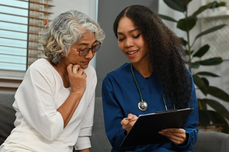 A nurse explains the results of the health exam to the elderly woman at home.